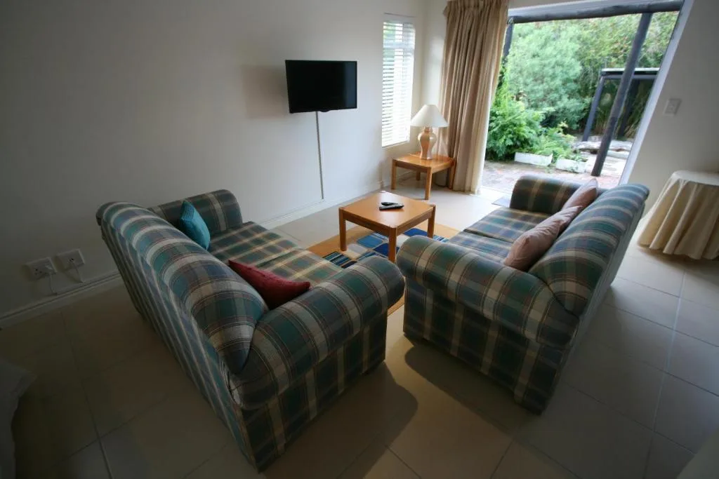 Spacious living room with striped armchairs, TV, and garden views