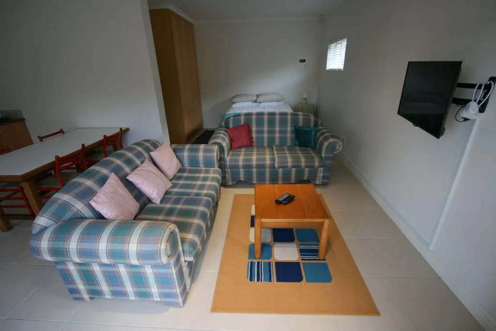 Spacious lounge with two plaid sofas, wooden coffee table, and wall-mounted television