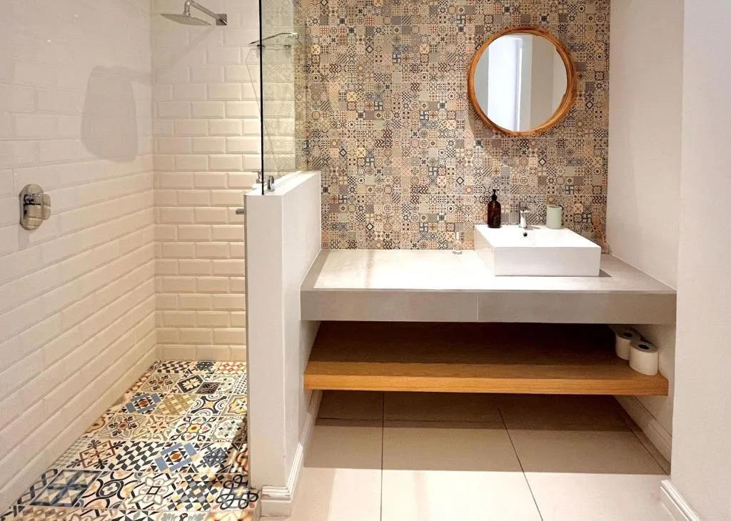 Modern bathroom with patterned tile wall, round mirror, white vessel sink
