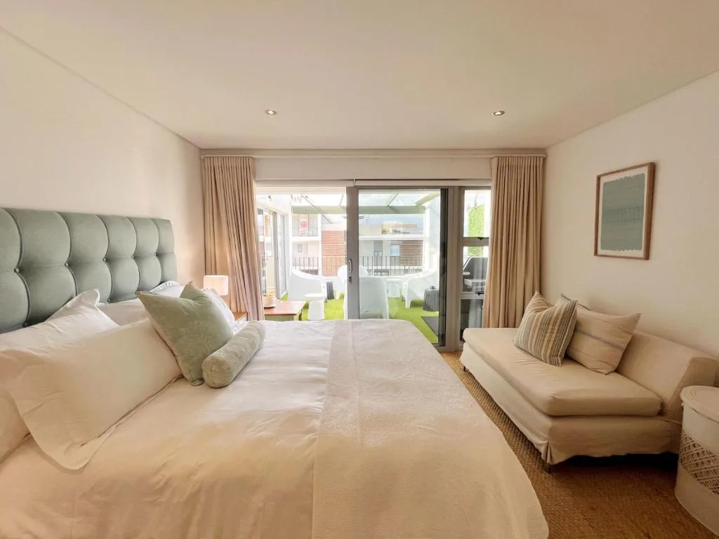 Spacious bedroom with queen bed, green headboard, and sliding doors to deck