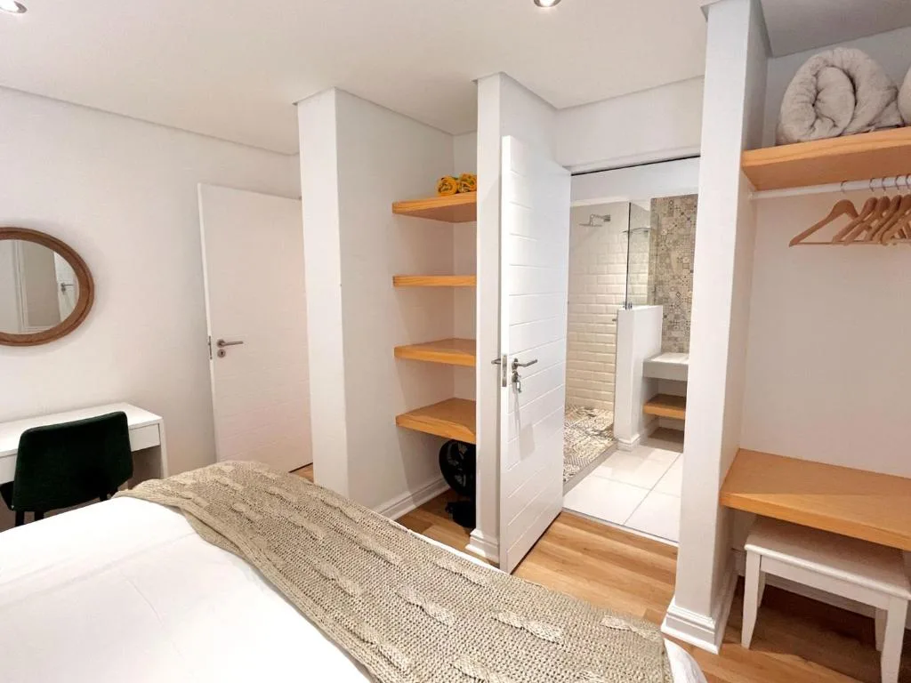 Modern bedroom with ensuite bathroom and wooden shelving storage