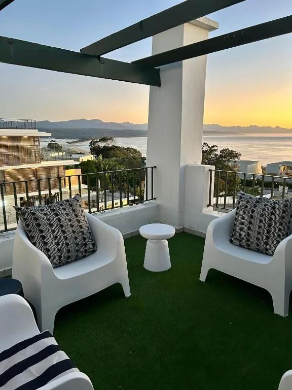 Modern outdoor deck with seating overlooking lagoon and mountains at sunset