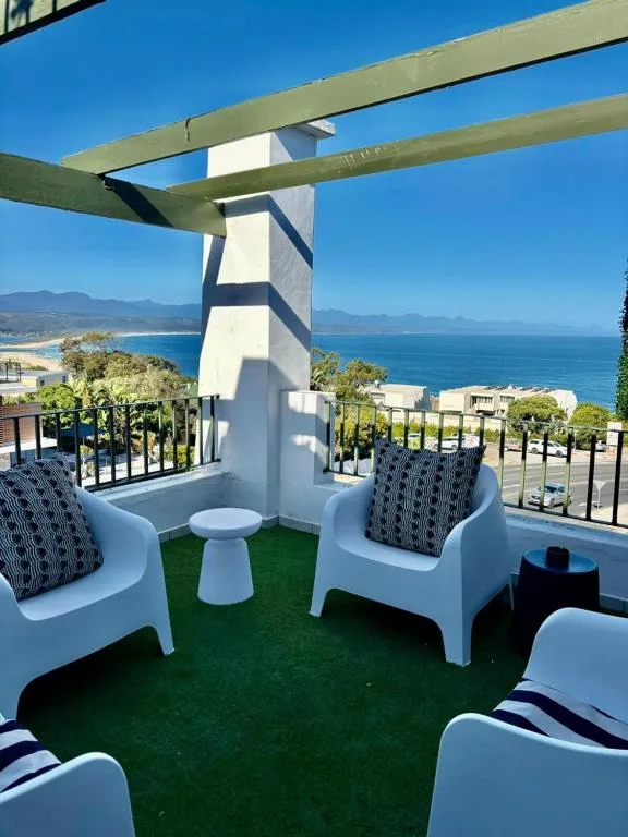 Elevated deck with lounge chairs overlooking coastal sea views and mountains