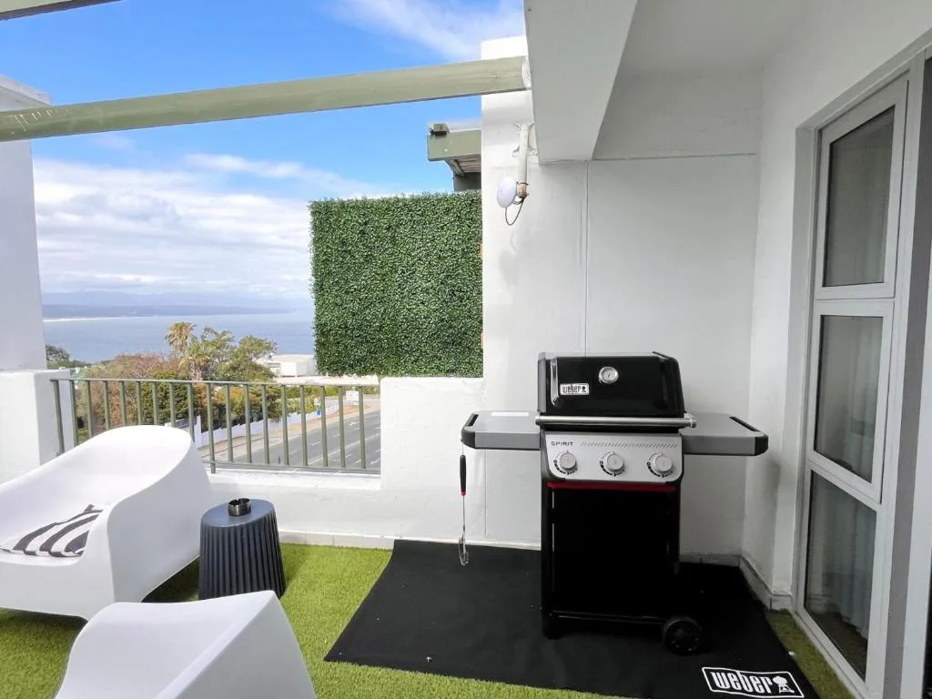 Outdoor deck with braai grill, seating, and ocean views from balcony