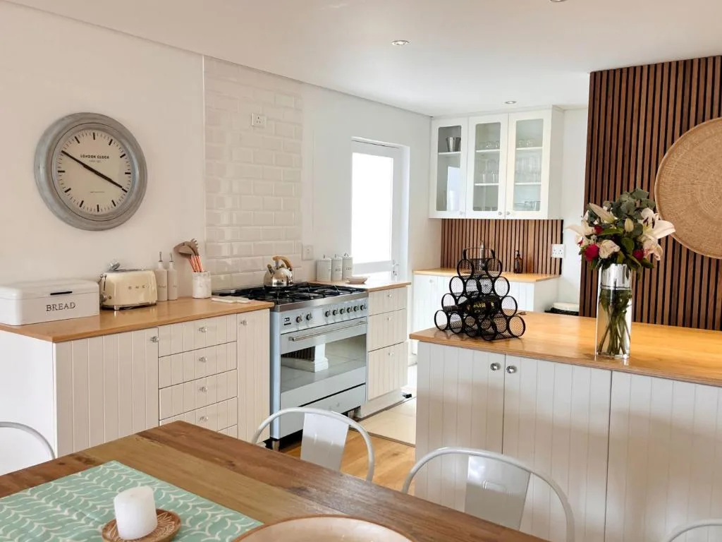 Modern kitchen with white cabinetry, wooden countertops, and stainless steel range