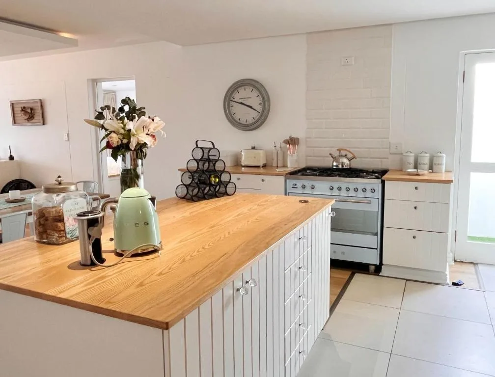 Modern kitchen with wooden island, gas range, and fresh flowers