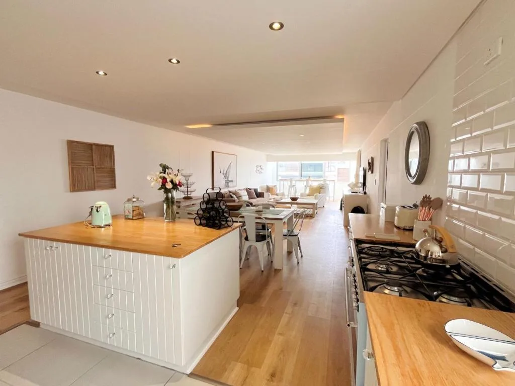 Modern open-plan kitchen with white cabinetry, wooden countertops, and gas range