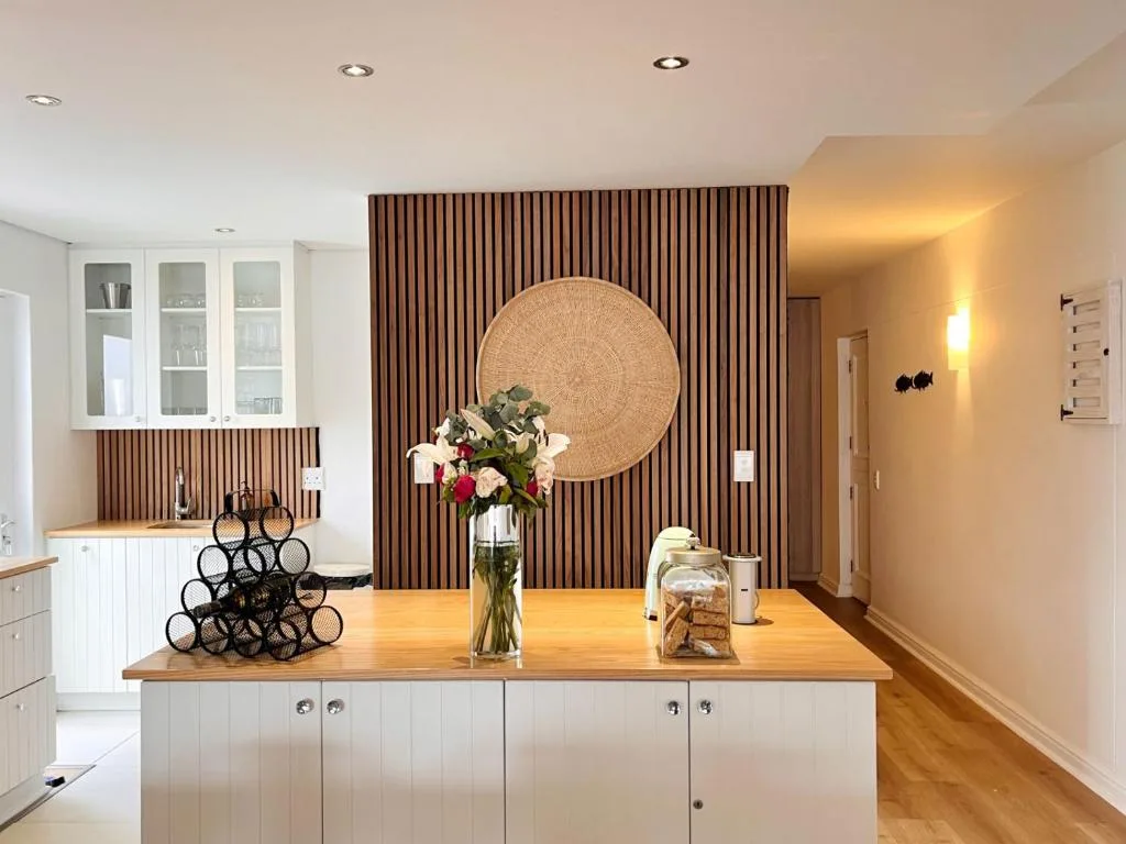 Modern kitchen with white cabinetry, wooden countertop, and decorative wall paneling