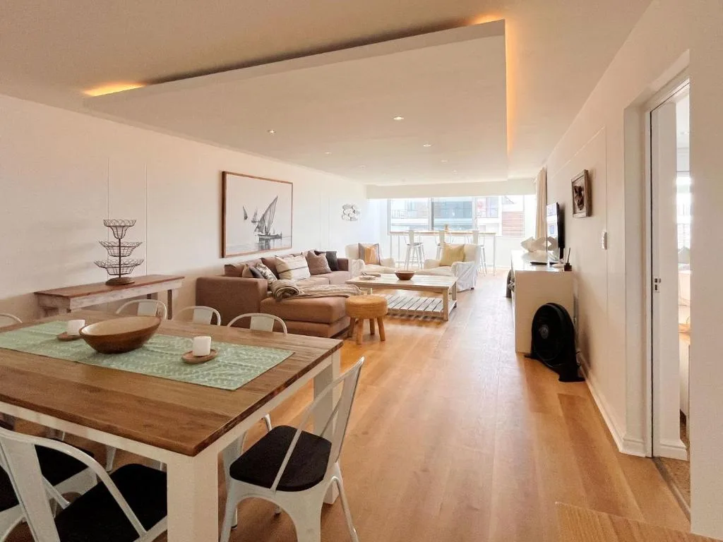 Modern open-plan living space with sofa, dining table, and ocean view windows