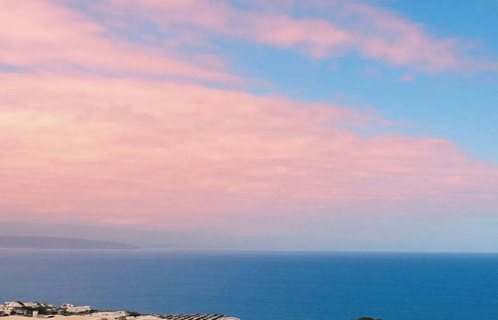 Scenic ocean view at sunset with pink sky and blue water horizon
