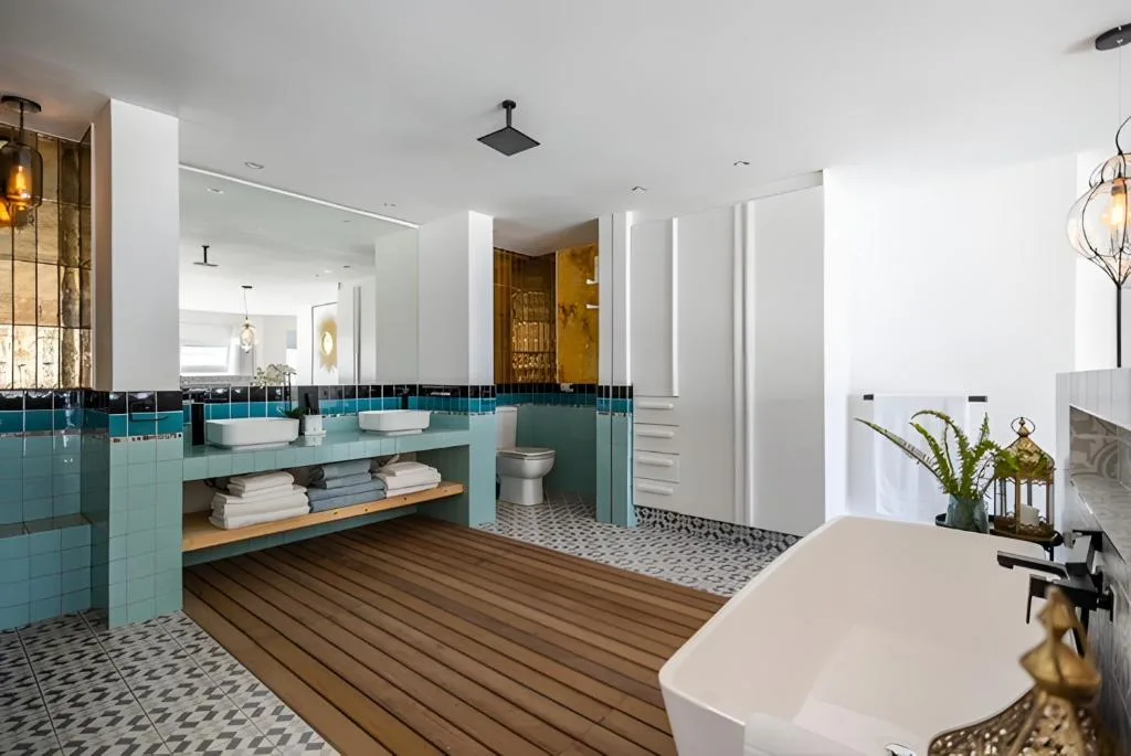 Spacious modern bathroom with turquoise vanity, freestanding tub, and patterned tile flooring