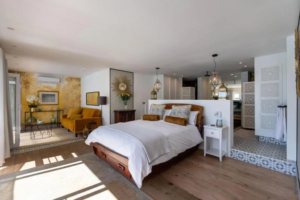 Spacious master bedroom with queen bed, golden accent chair, and ocean views