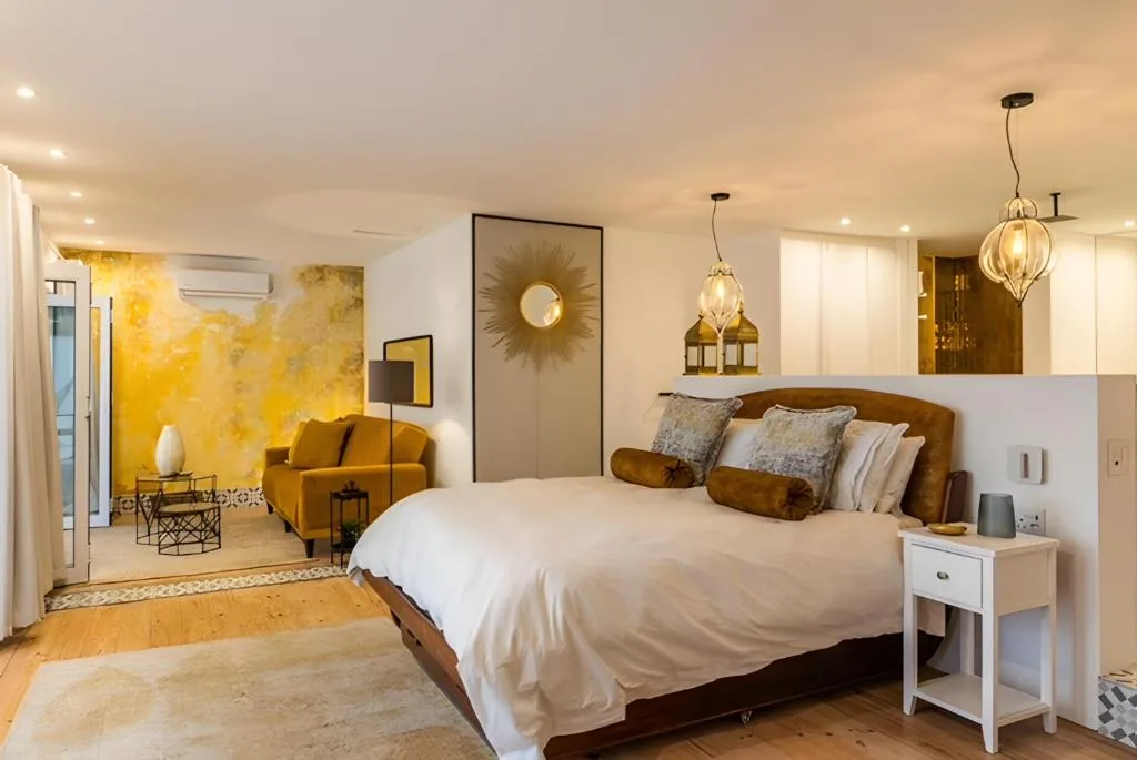 Luxurious bedroom with king bed, mustard lounge area, and pendant lighting