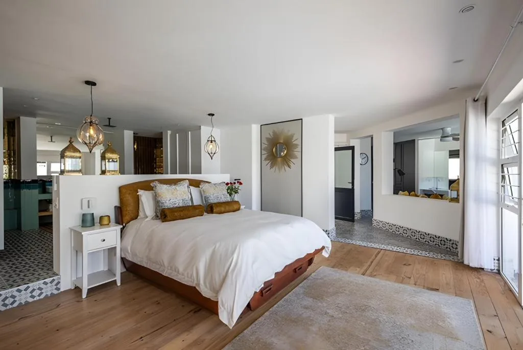 Spacious modern bedroom with queen bed, gold accents, and en-suite bathroom