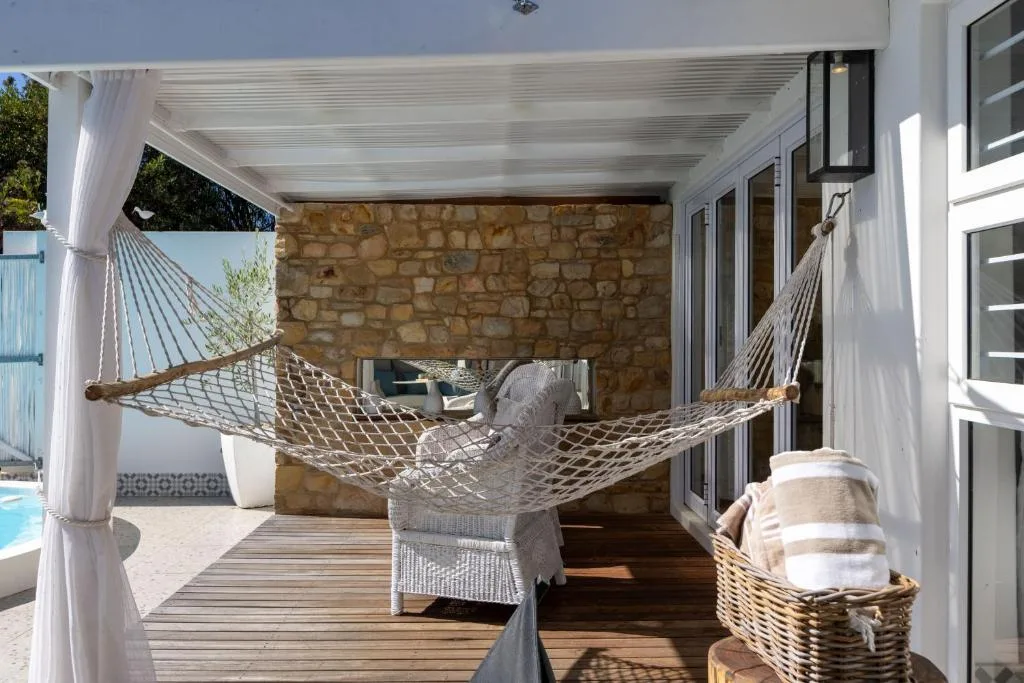Shaded patio with hammock, white curtains, and stone wall accent