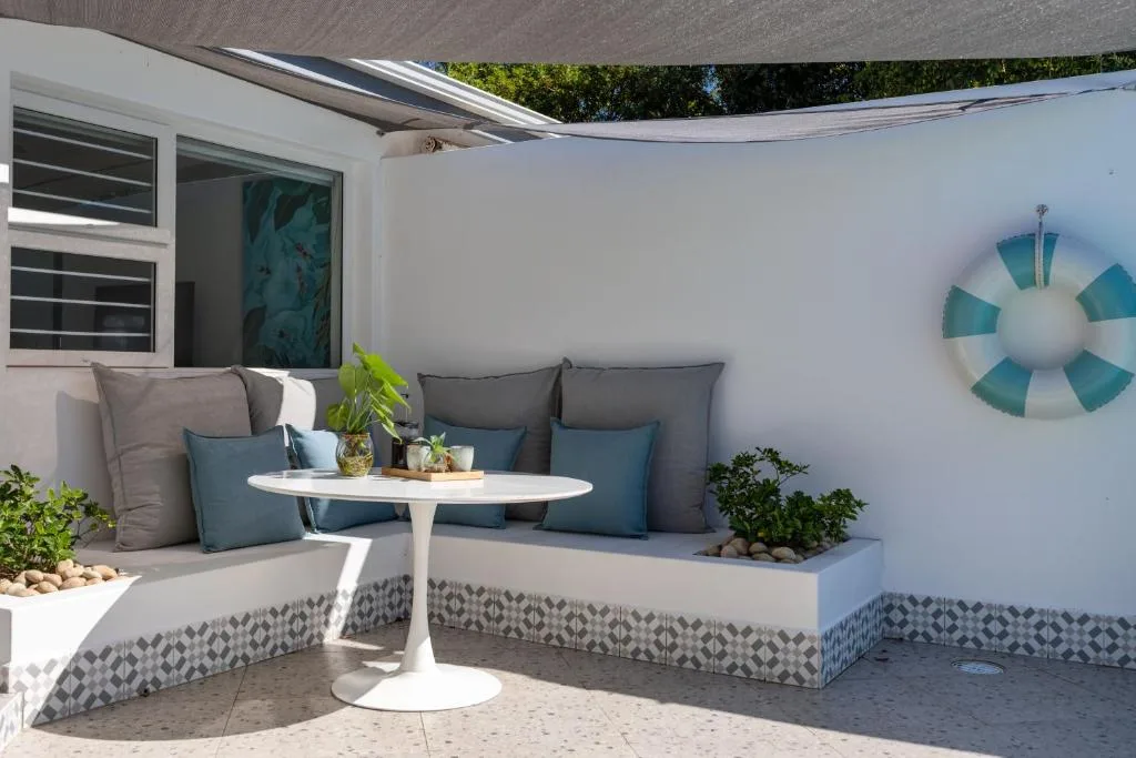Outdoor seating area with cushioned bench, round table, and shade covering