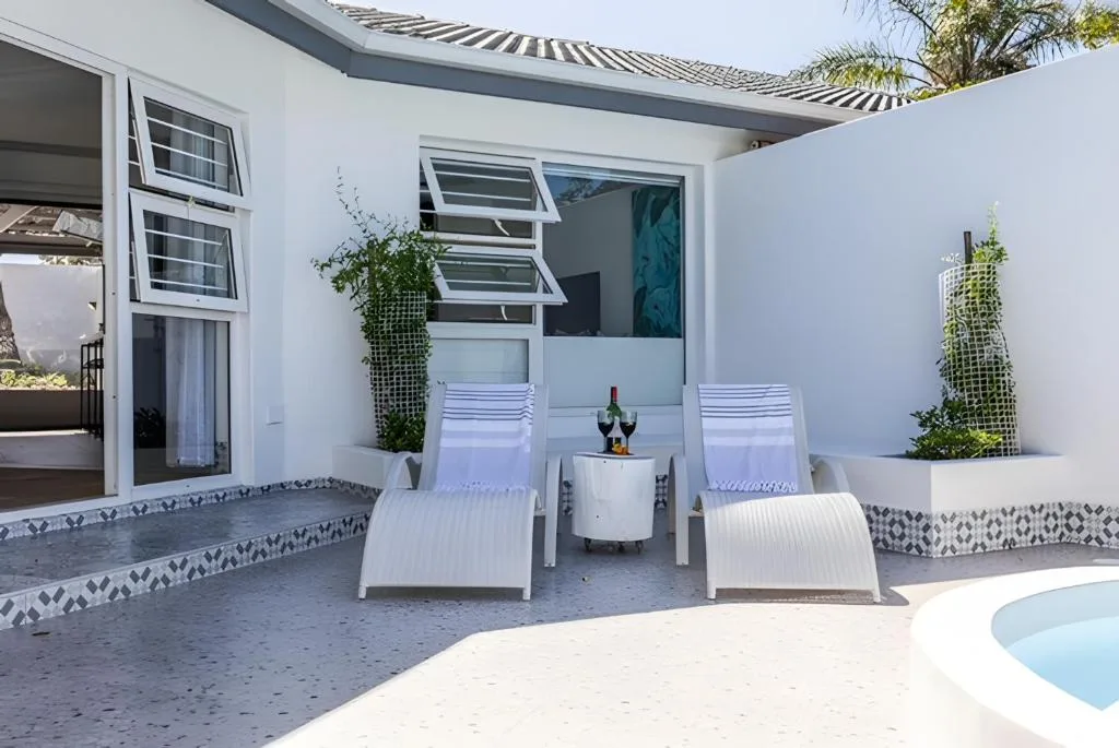 Modern courtyard patio with loungers, potted plants, and white architecture