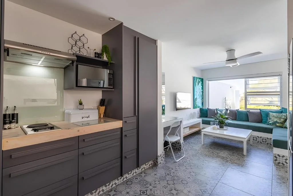 Modern kitchen with dark cabinetry and lounge area visible beyond