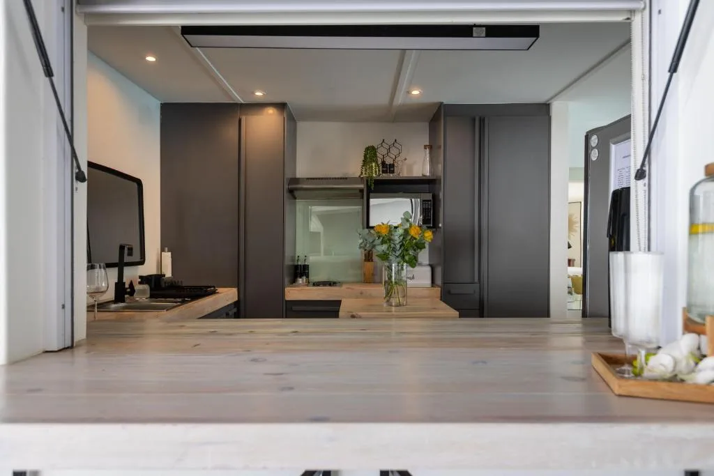 Modern kitchen with dark cabinetry, wooden countertops, and fresh flowers in vase