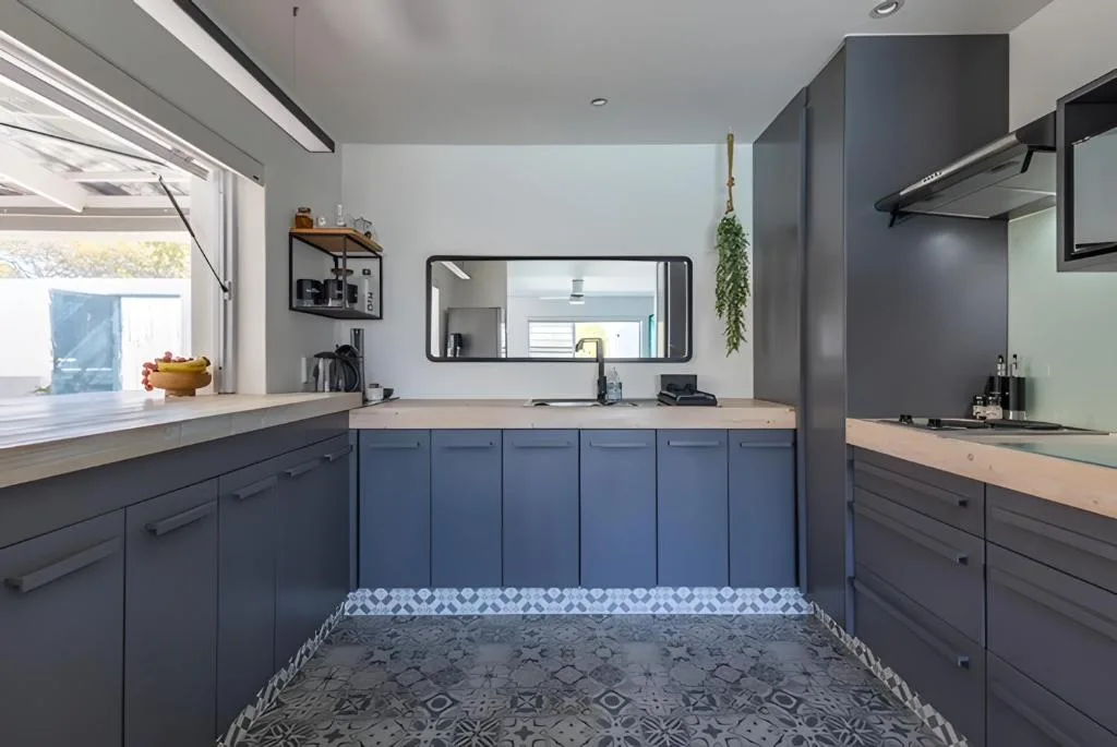 Modern kitchen with blue cabinetry, wooden countertops, and stainless steel appliances