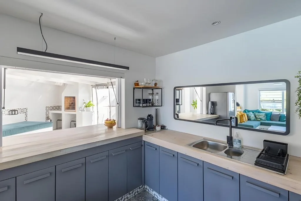 Modern kitchen with blue cabinetry, light wood countertops, and stainless steel sink