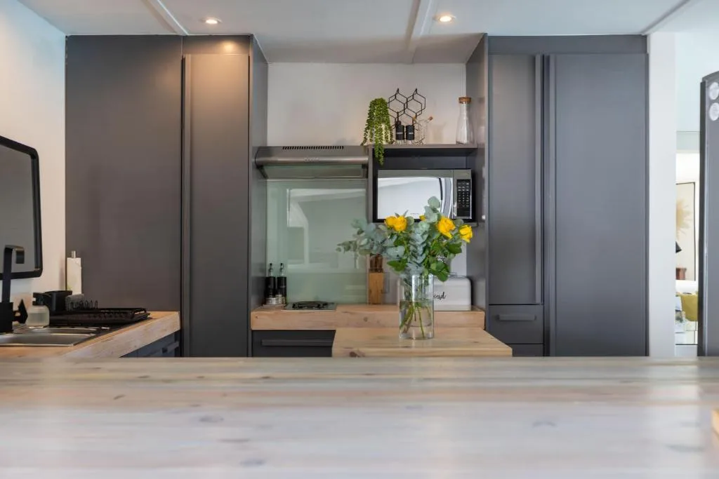 Modern kitchen with dark cabinetry, wooden counters, and fresh flowers