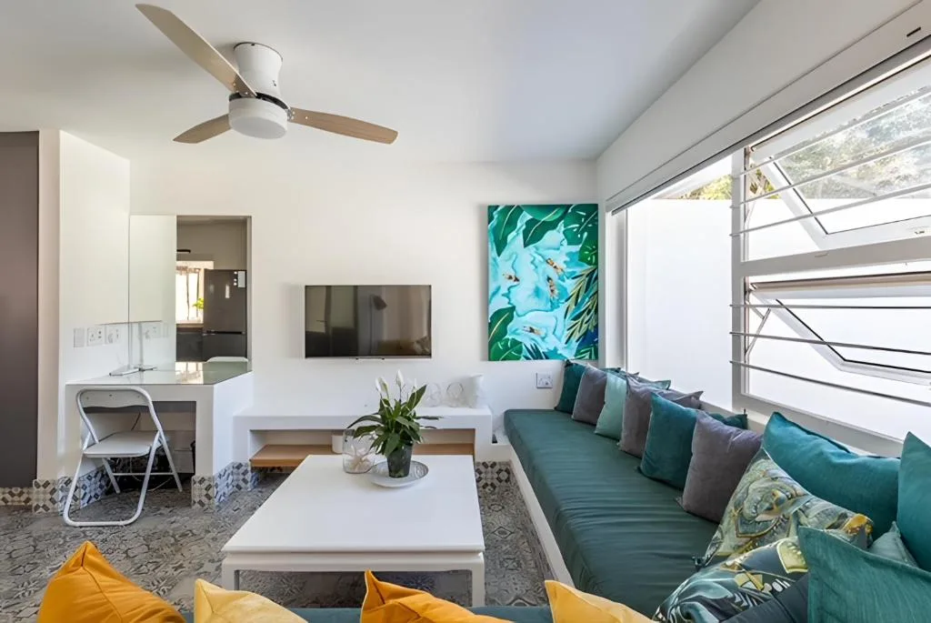 Modern lounge with teal sofa, yellow cushions, and ocean view through large windows