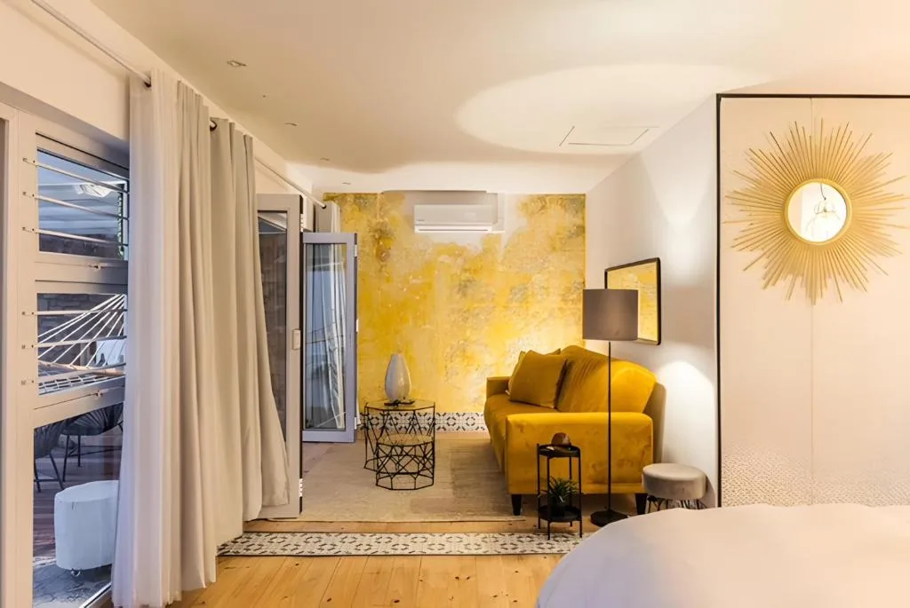 Modern lounge with mustard yellow armchair, geometric decor, and ocean view access