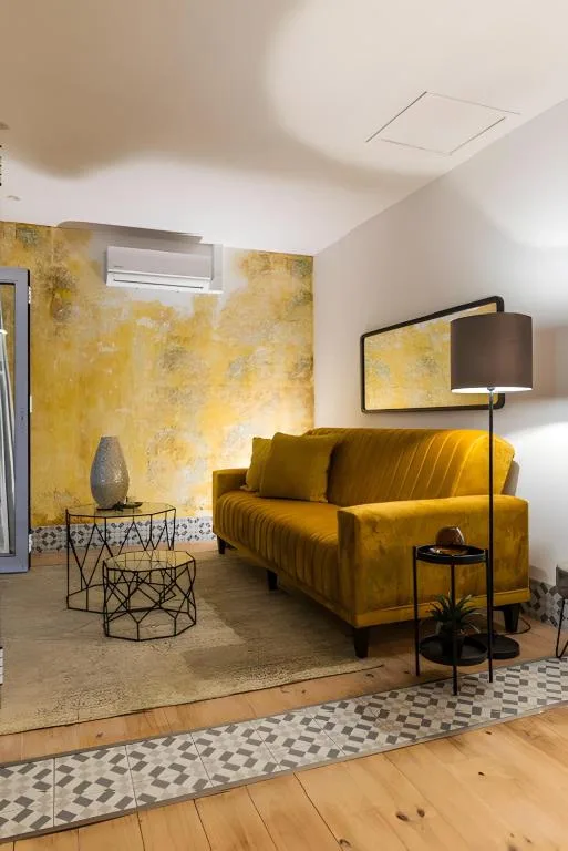 Modern lounge with golden sofa, floor lamp, and textured yellow accent wall