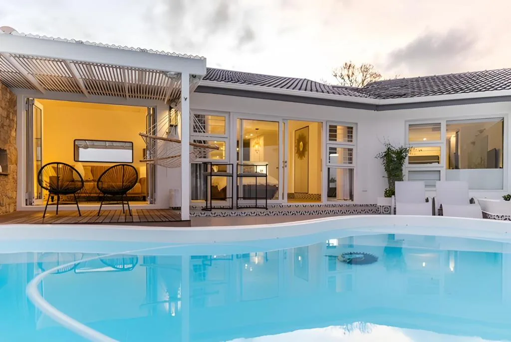 Sparkling blue swimming pool with modern house and deck area at dusk