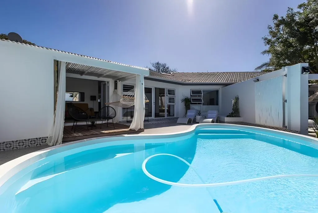 Bright turquoise swimming pool with white modern villa and shaded patio area