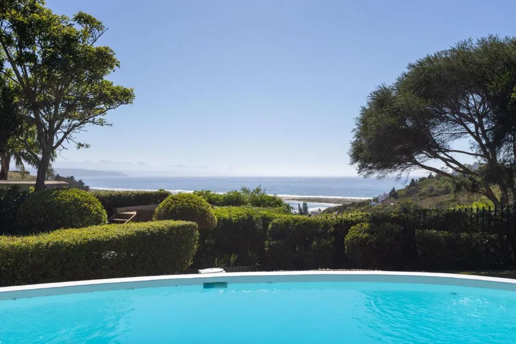 Sparkling blue swimming pool overlooking ocean and coastal landscape beyond