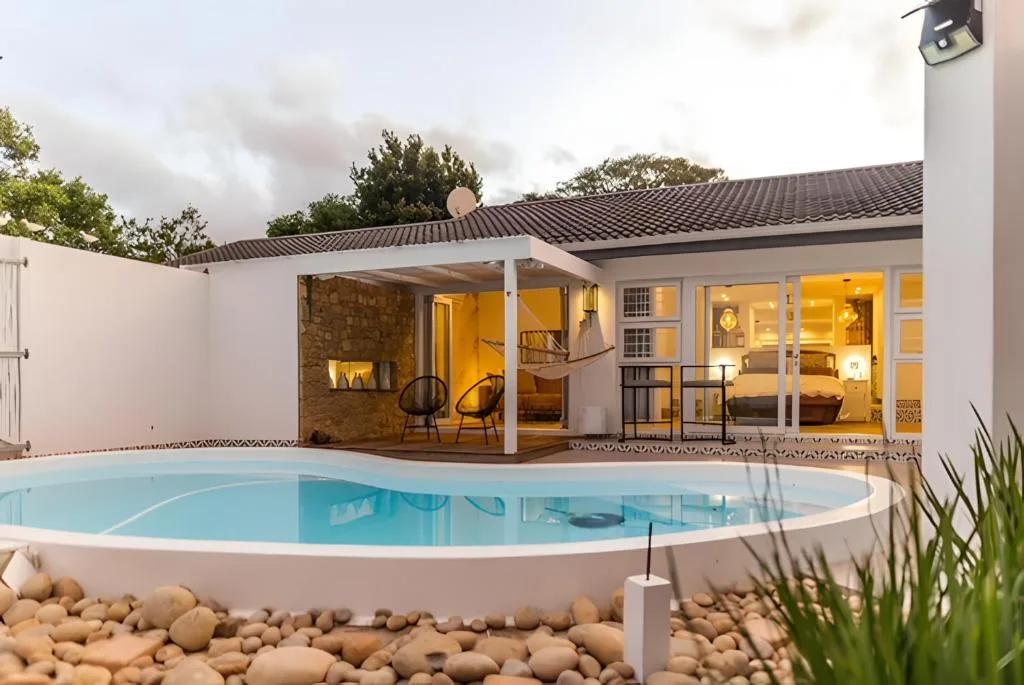 Illuminated modern home with curved swimming pool at twilight