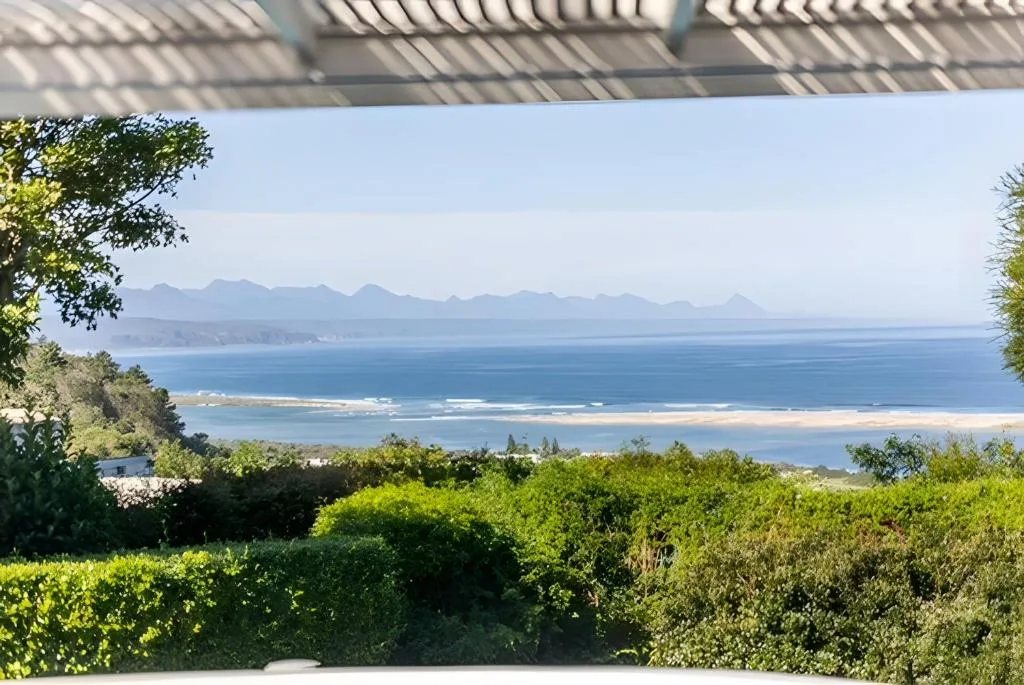 Ocean vista with mountains visible across blue waters from covered deck