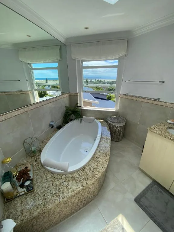 Luxurious freestanding bathtub with lagoon views through floor-to-ceiling windows
