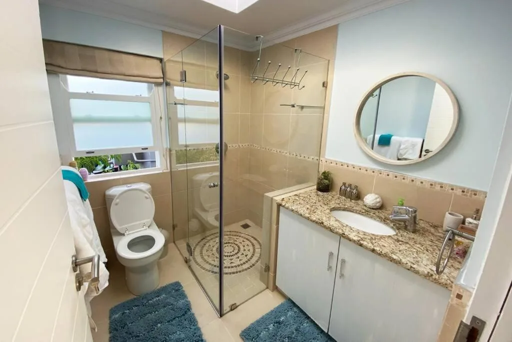 Modern bathroom with walk-in shower, double vanity, and round mirror