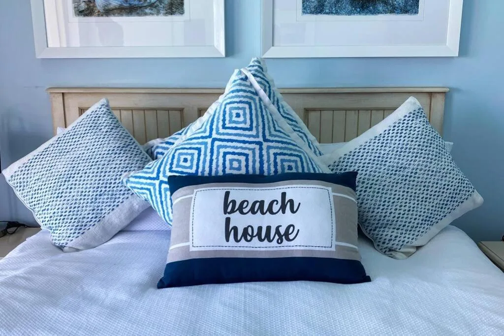 Coastal-themed bedroom with decorative beach house pillows and light blue walls