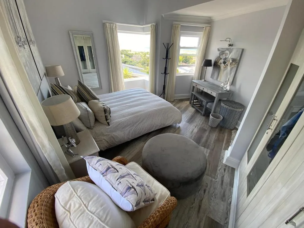 Bright bedroom with striped bedding, open doors to lagoon views, and modern furnishings