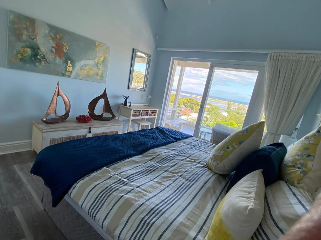 Bright bedroom with ocean views through glass doors and coastal decor