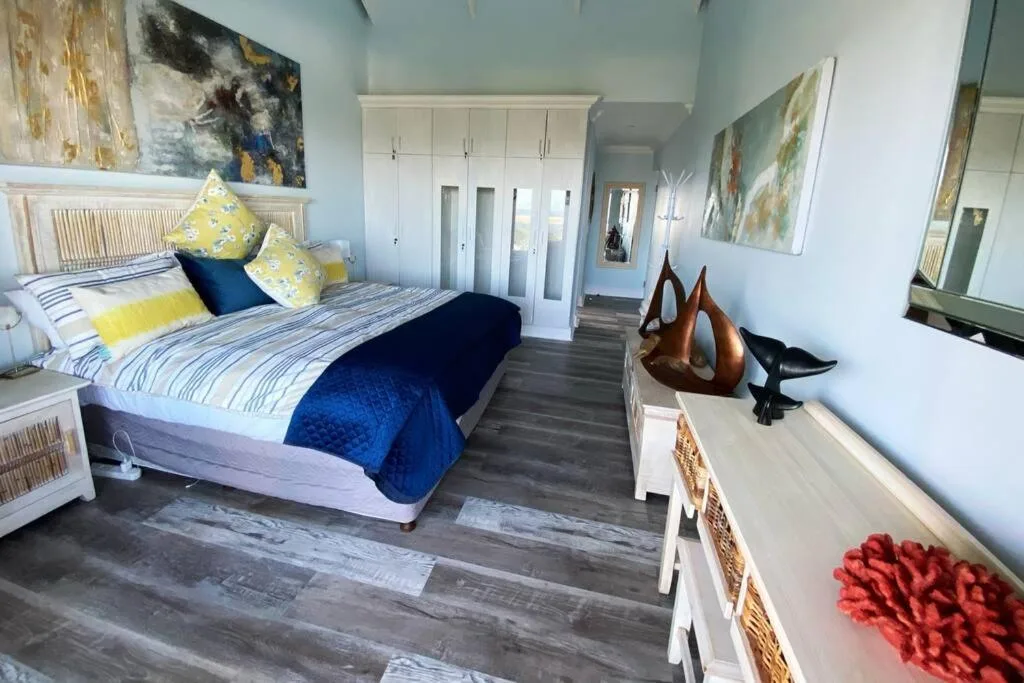 Bright bedroom with queen bed, yellow pillows, blue accents, and built-in wardrobes