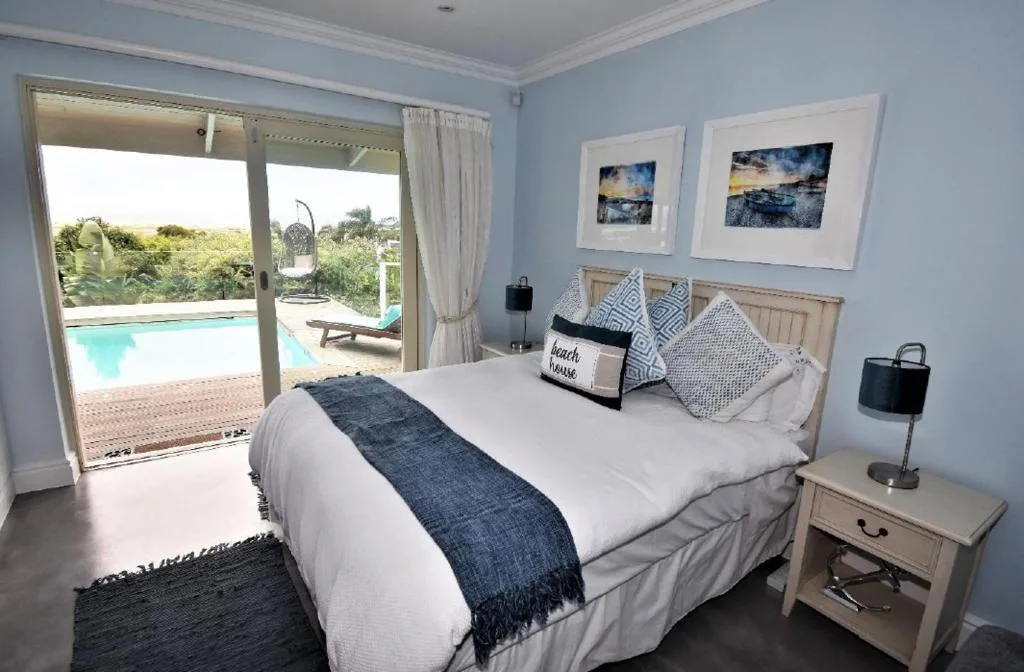 Bright bedroom with queen bed overlooking pool and garden views through patio doors