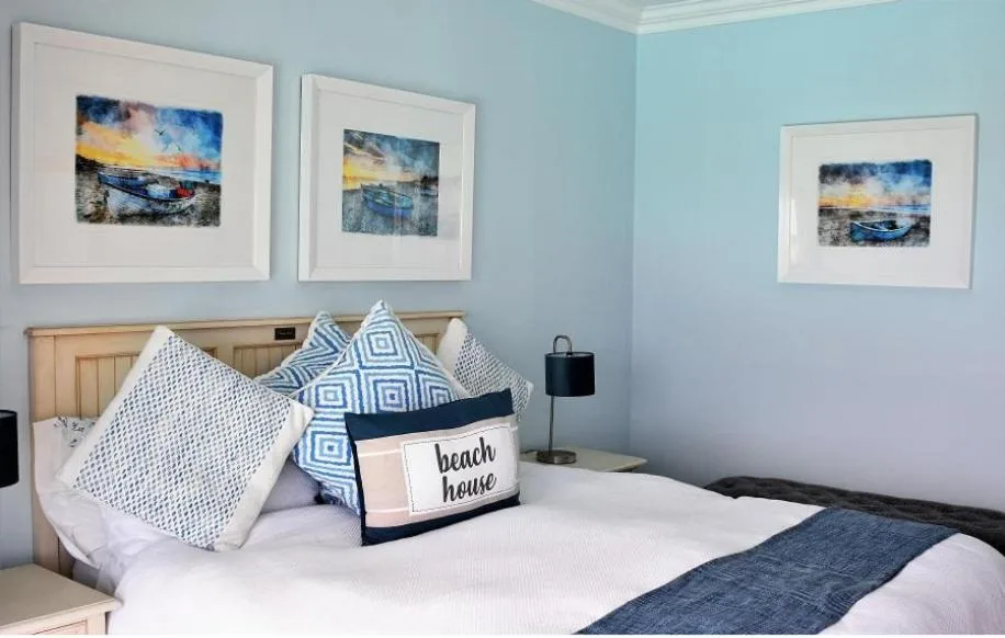 Coastal-themed bedroom with blue walls, wooden headboard, decorative pillows