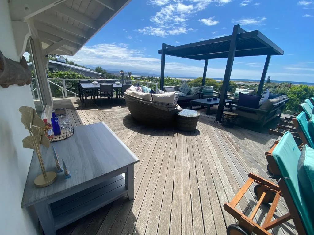 Expansive wooden deck with ocean views, lounge seating, and pergola