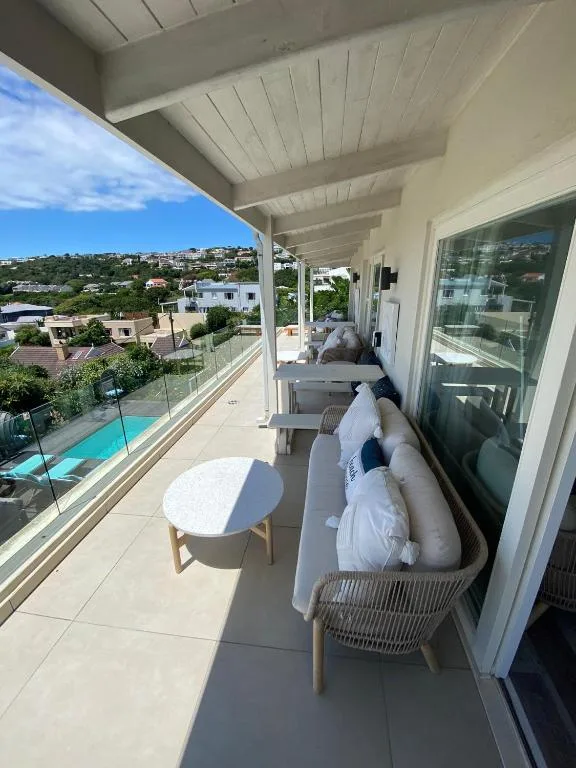 Covered balcony with lounge seating overlooking hills and pool area