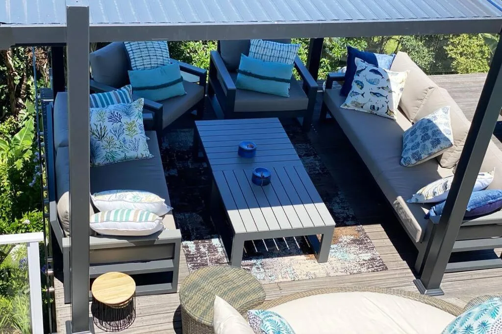 Covered outdoor deck with lounge seating, coffee table, and garden views