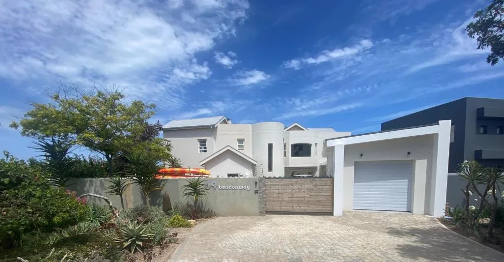 Modern white villa with garage and manicured gardens under blue sky