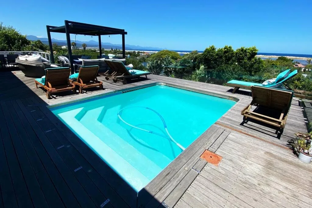 Sparkling turquoise swimming pool with ocean and mountain views beyond