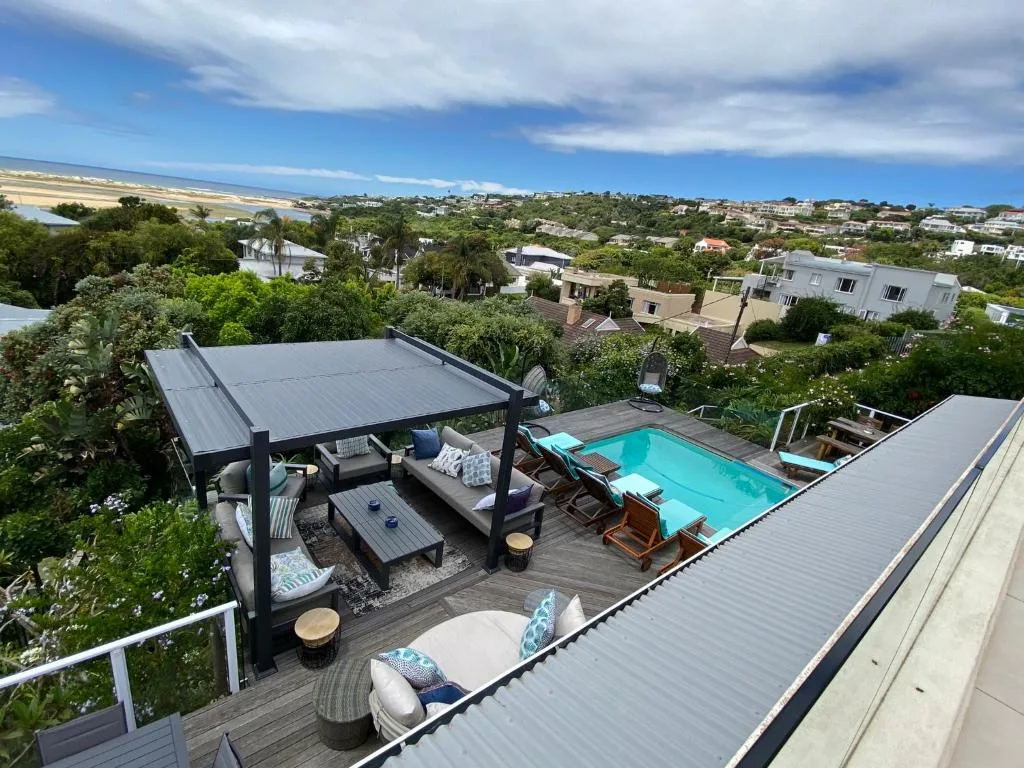 Sparkling turquoise swimming pool with loungers, shaded pergola, and coastal views