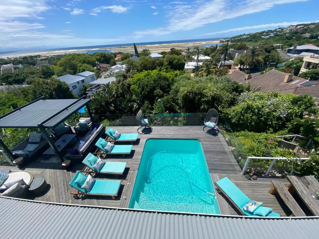 Turquoise swimming pool with loungers overlooking ocean and beach landscape