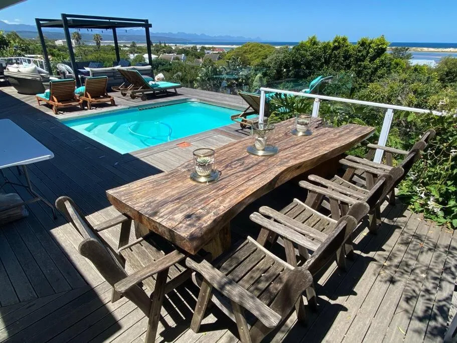 Sparkling turquoise swimming pool with wooden deck and ocean view
